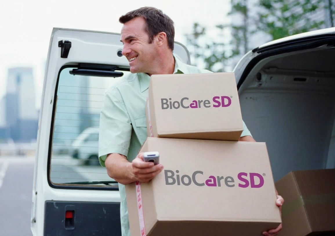 Delivery person carrying boxes labelled with BioCareSD logo